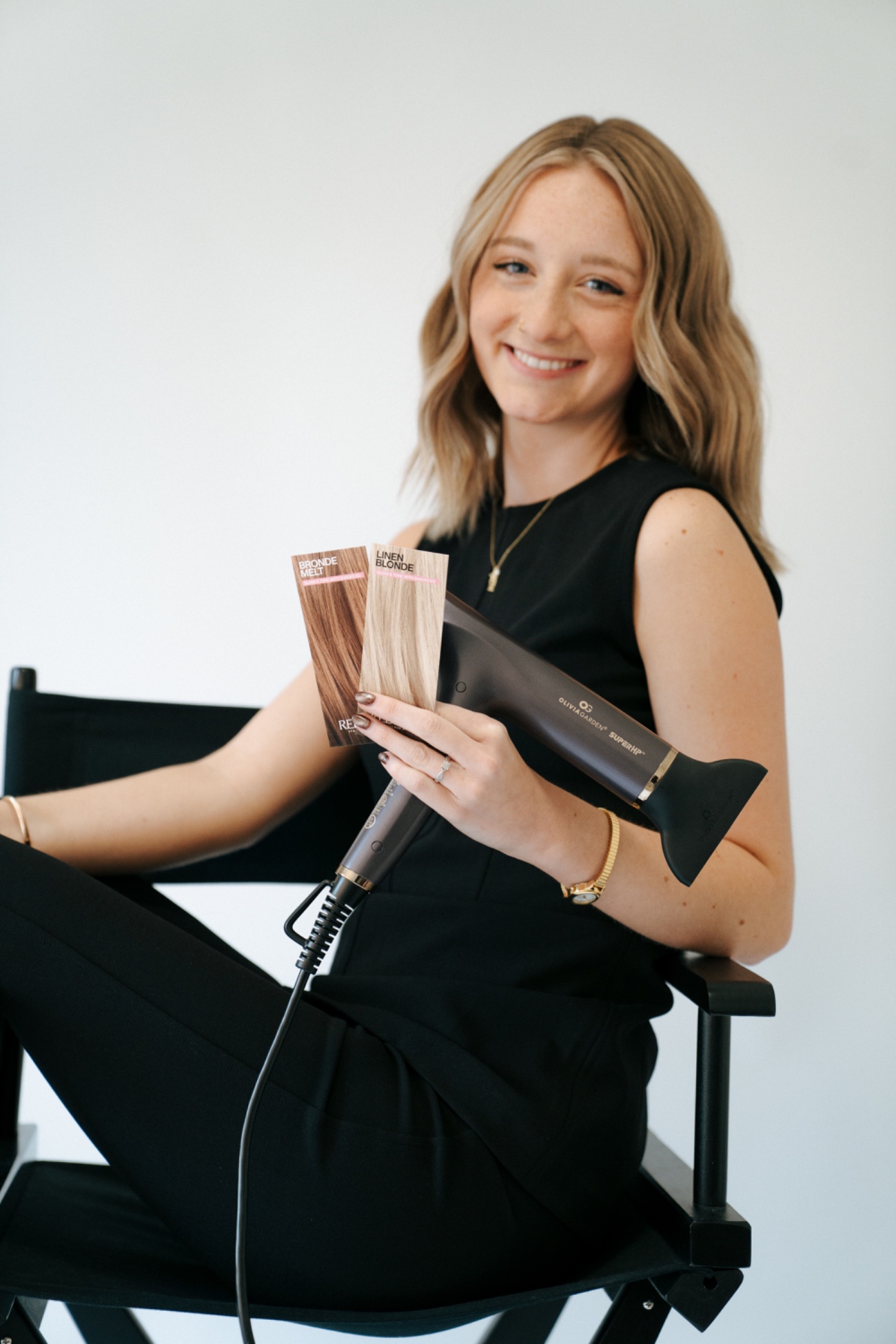 Brooklyn holding a curling iron and a dryer in her studio.
